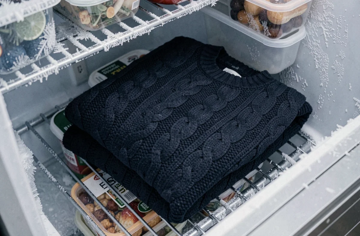Pull en laine bleu marine plié dans un tiroir congélateur entouré de givre